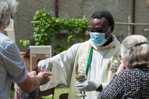 Priest celebrates the Mass during covid-19 lockdown. The faithful receive the Holy Host, wearing gloves and protective masks. Priest eucharist stock images, royalty-free photos and pictures