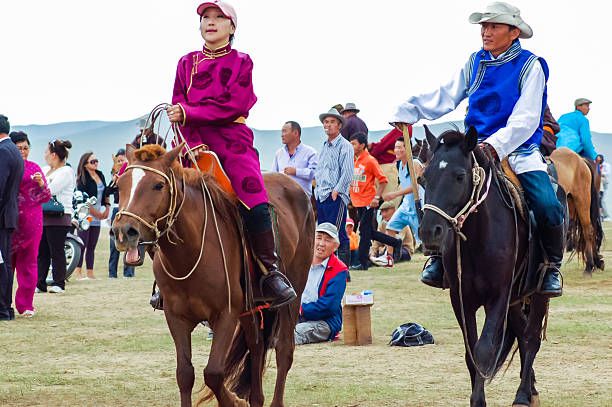 Horseback spectators at Nadaam horse race Khui Doloon Khudag, Mongolia - July 12, 2010: Horseback spectators in traditional costume at Nadaam horse race on steppe outside the capital Ulaanbaatar. Nadaam or the “Three Manly Games” is the most important festival of the year in Mongolia from 11-13 July. Its roots lie in Mongolian warrior traditions. Competitions include horse racing, Mongolian wrestling and archery. mongolia horse racing stock pictures, royalty-free photos & images
