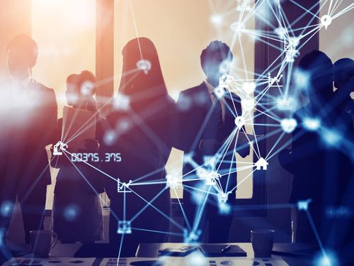 Group of professionals in front of computer screen with network connections.