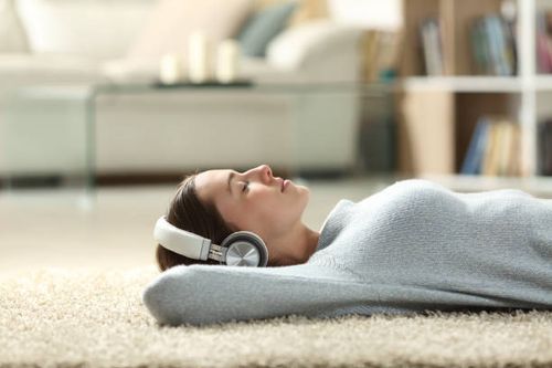 Relaxed woman listening to music with headphones at home Side view portrait of a relaxed woman listening to music with headphones lying on a carpet at home calm-person stock pictures, royalty-free photos & images