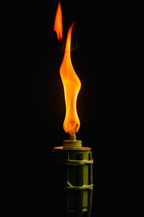Free Close-up of a lighted torch with orange flame against a black background. Stock Photo