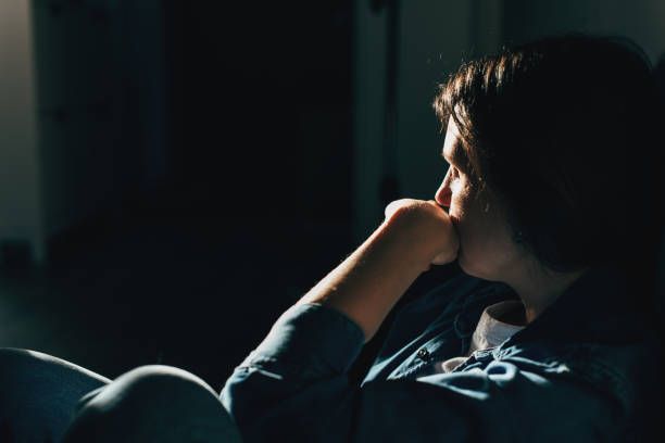 silhouette of sad and depressed woman sitting on the floor at home - víctima fotografías e imágenes de stock