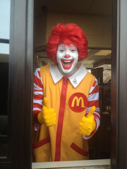 a man dressed as a ronald mcdonald clown giving the thumbs up while standing in an elevator