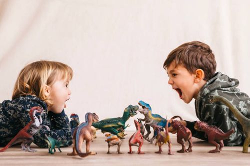 brother and his little sister playing with toy dinosaurs - dinosaur images for kids stock pictures, royalty-free photos & images