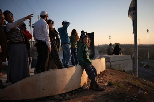 Right-wing Israeli settlers gather on a hill overlooking the Gaza Strip in Sderot in southern Israel on December 18, 2025. (Photo by Ilia YEFIMOVICH / AFP)