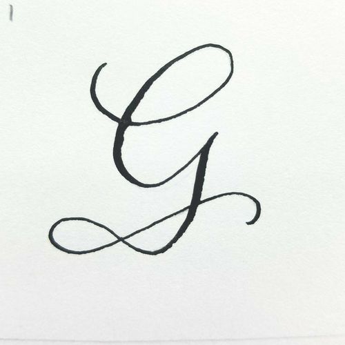 the letter g is written in cursive writing with black ink on white paper