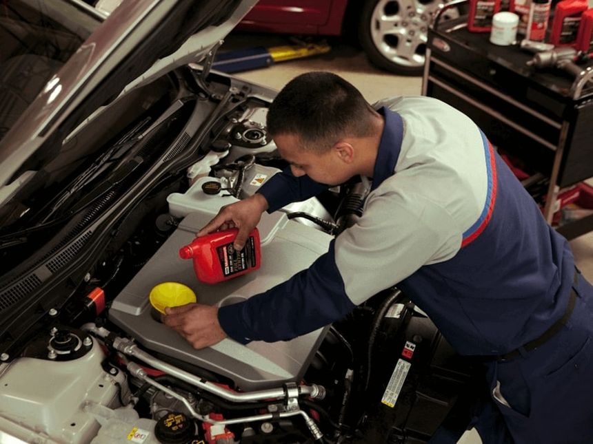 Ford technician performing oil change service under hood at Irvine Ford