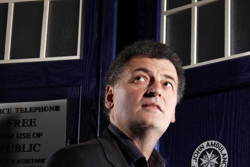 Steven Moffat standing outside the TARDIS looking up.