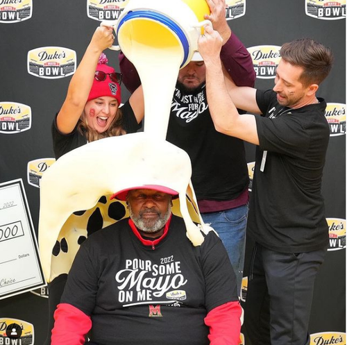 A Giant cooler of Duke's Mayo being poured on a man's head