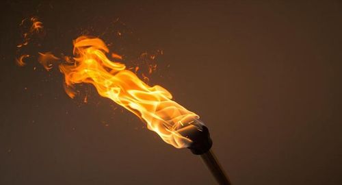 Burning Torch with Vibrant Flames and Flying Embers Against a Dark Background photo