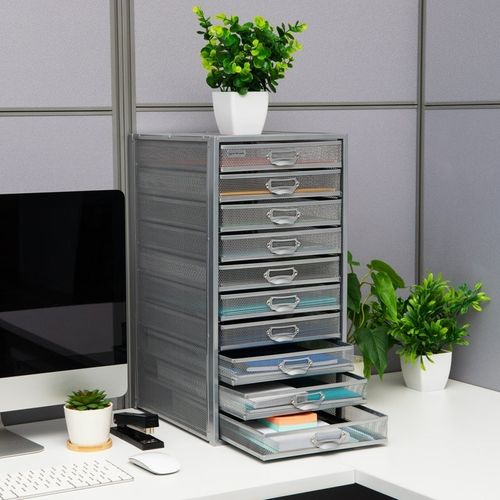 Desk organizer with multiple drawers, holding stationery items, next to a computer monitor; plants decorate the office space