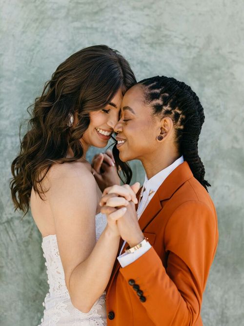 Cute Couple Poses: Couple hold hands and face each other while smiling.