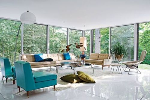 A mid-century modern living room with glazed walls, tan and turquoise seating furniture, a low coffee table and pillows and lamps.