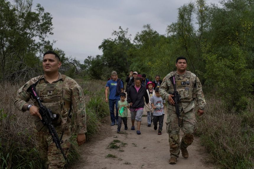 Migrants from Central America and China are escorted by members of the Texas Army National Guard.