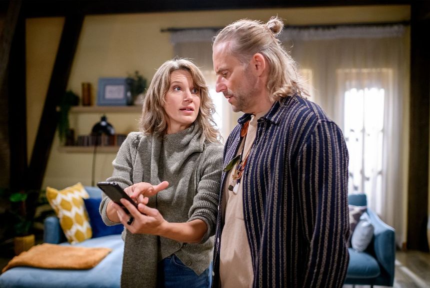 Anja steht zusammen mit Michael im Appartement. Sie zeigt ihm etwas auf ihrem Handy und schaut ihn dabei an!