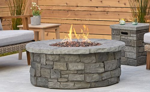 Stone fire pit on a patio with wooden walls.