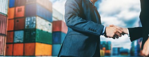 export and import business. businessmen handshake at industrial container terminal. maritime transport and logistics concept