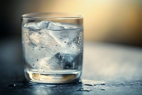 A glass of ice cold water with condensation on a table