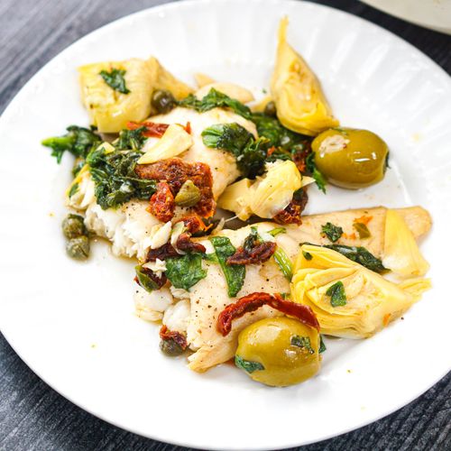 white plate with a serving mediterranean fish dinner