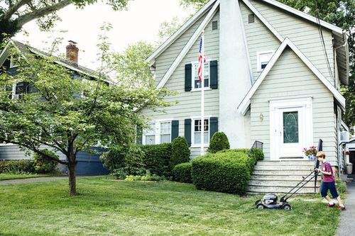 Boy mowing front lawn