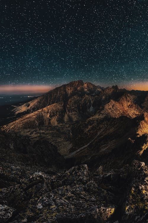 Free Stunning starry night sky over rugged mountains, perfect for nature lovers. Stock Photo