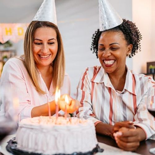 adult woman lighting the candles for her friend's birthday at home
