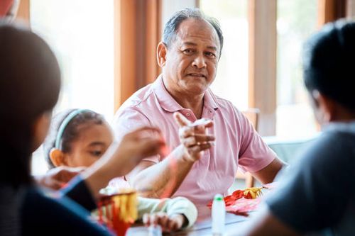 man talking while making wau bulan with family - wau malaysia stock pictures, royalty-free photos & images