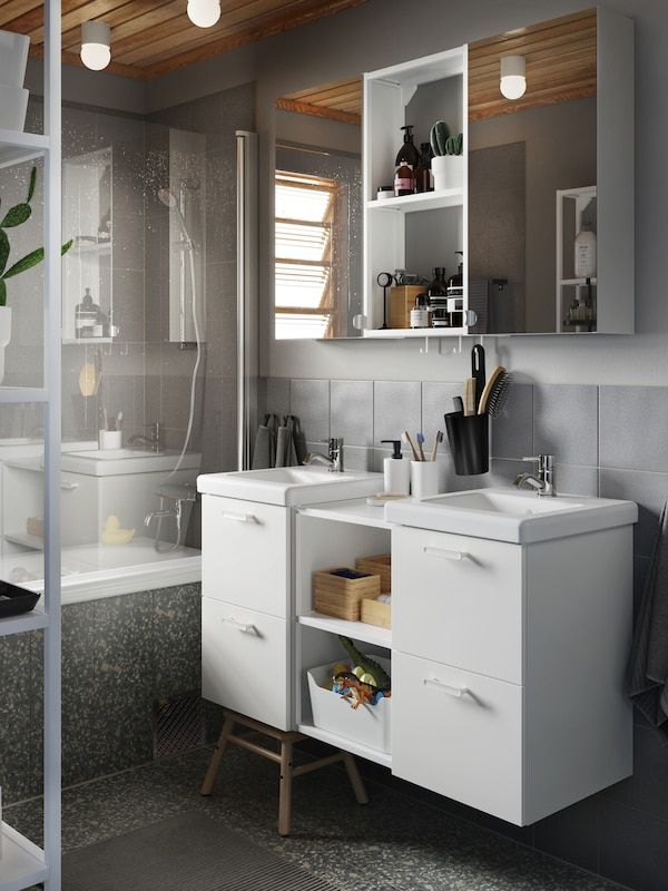 Phòng tắm màu xám với hai bồn rửa màu trắng, hai tủ âm tường có cửa gương, khăn tắm và thảm tắm màu xám.