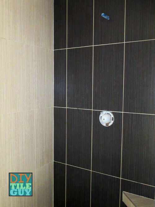 Two shower walls each with a different color of 12x24 tiles installed vertically in a straight-lay, or stacked tile pattern