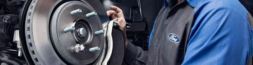 Certified Ford technician inspecting brake rotor and brake pads during service in Irvine CA