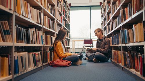 十几岁的男孩和女孩微笑着在图书馆学习照片下载