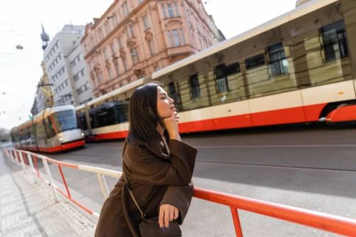 Side view of brunette woman in coat looking at trams on street in Prague  - Photo, Image
