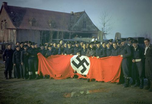An allied aircrew display a tattered German swastika at an airbase in Holland.