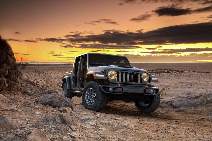 Jeep Wrangler driving over rocky desert terrain at sunset showcasing Trail Rated off-road capability