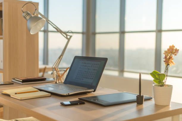 Side view picture of studio workplace with blank notebook, laptop. Comfortable work table, home office. Side view picture of studio workplace with blank notebook, laptop. Designer comfortable work table, home office home office desk window stock pictures, royalty-free photos & images