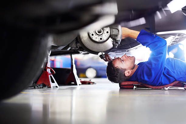Certified automotive technician performing undercarriage inspection and brake service at Tuttle-Click Tustin Chrysler Jeep Dodge Ram in Tustin, CA