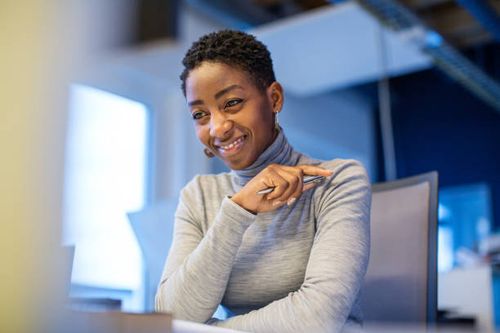 confident african businesswoman sitting at her desk - professional woman at desk stock pictures, royalty-free photos & images