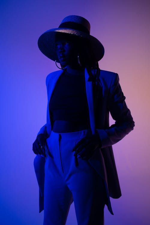 Free Portrait of a stylish woman in suit and hat with dramatic blue and pink lighting. Stock Photo