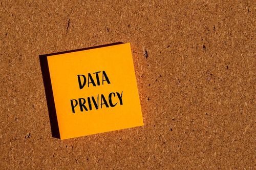 Photo data privacy words written on orange paper sticker with brown background