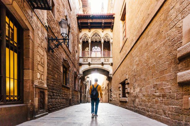 young man with backpack walking on the streets of gothic quarter in barcelona, spain - gothic quarter barcelona stock pictures, royalty-free photos & images