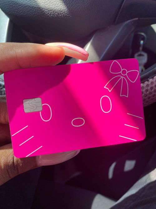 a person holding a pink credit card in their hand with a bow on it's head