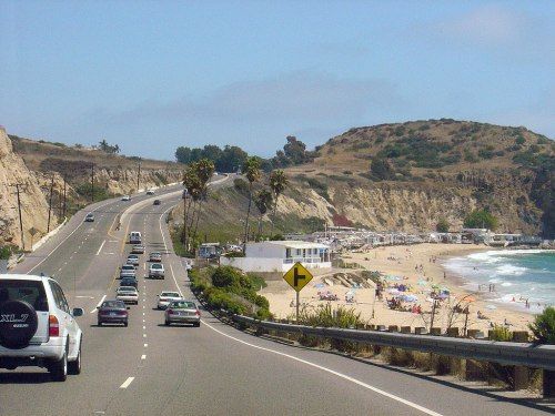 Cars driving along Pacific Coast Highway in Orange County with ocean and beach views