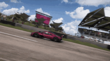 a red sports car is driving down a road