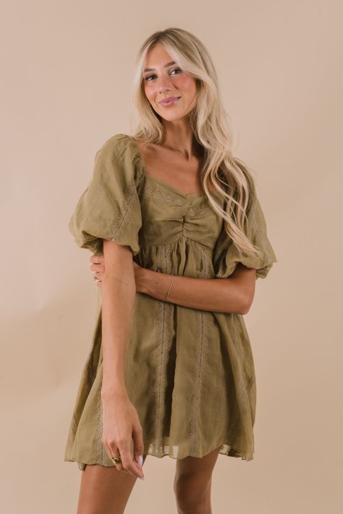This playful mini dress in a charming faded olive hue features short puff sleeves and a sweetheart neckline for a flirty touch. Delicate geometric embroidery with eyelet details adds a unique, whimsical flair, while the shirred back panel ensures a comfortable, flattering fit. Perfect for sunny days and fun nights out! Details Faded olive colored dress Mini length Short, puff sleeves Geometric embroidery with eyelet details Sweetheart neckline Fully lined Shirred panel in back Sizing *Measuremen
