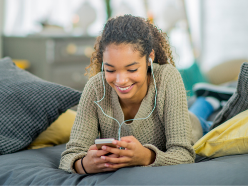 Young women smiles while listening to an audiobook on her phone