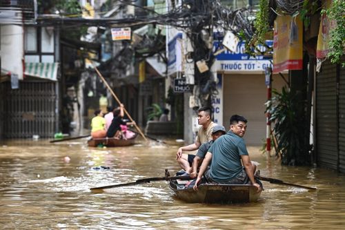 people in a boat in a flooded street with buildings in the background