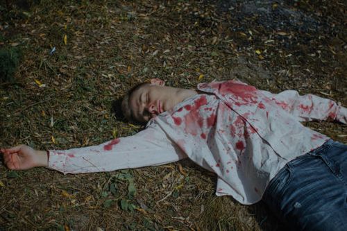 un joven muerto está tirado en el suelo con una camisa ensangrentada - hombre muerto suelo fotografías e imágenes de stock