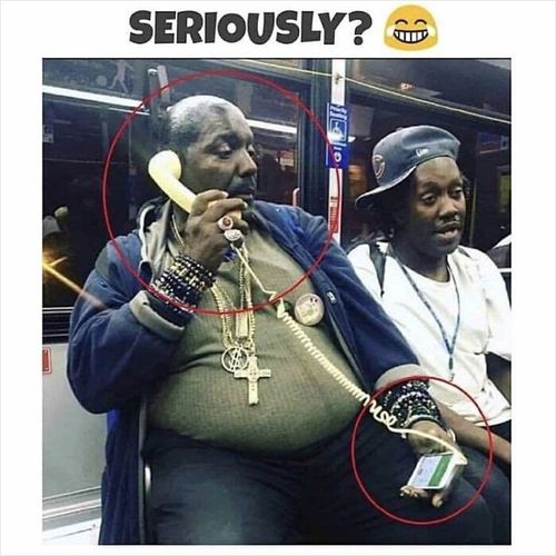 Man using a vintage phone handset plugged into a smartphone, with red circles highlighting this obvious contrast.