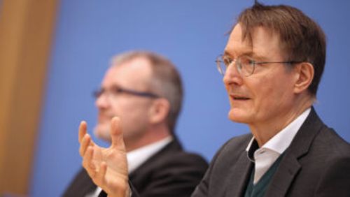 Bundesgesundheitsminister Karl Lauterbach (SPD) gestikuliert bei einer Pressekonferenz vor blauem Hintergrund