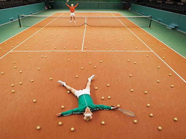 two men either side of tennis court, one lying on ground amongst balls - rendirse fotografías e imágenes de stock
